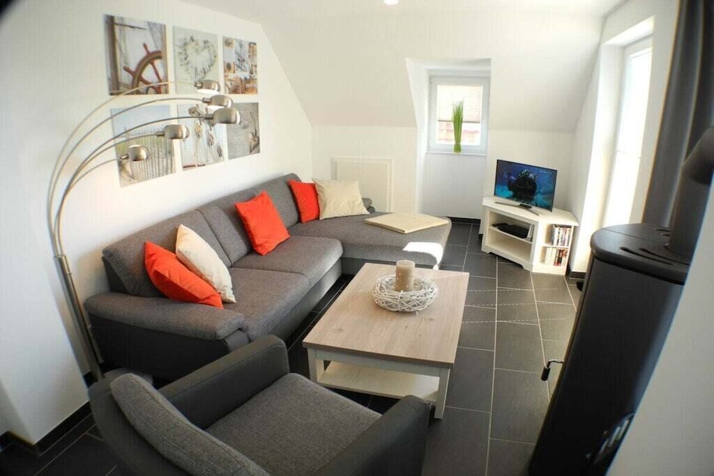 A modern living room with a grey sectional sofa, a small wooden coffee table, a TV on a stand, and a bookshelf.