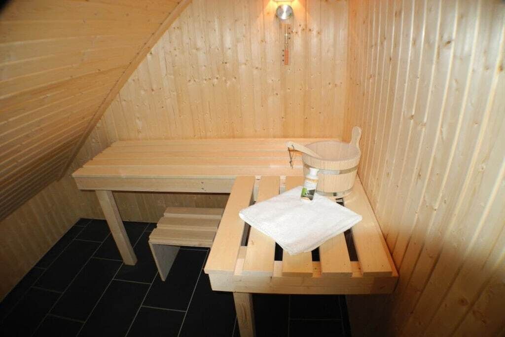 A sauna room with a wooden bench, a small table with a towel, and a wooden bench with a towel.
