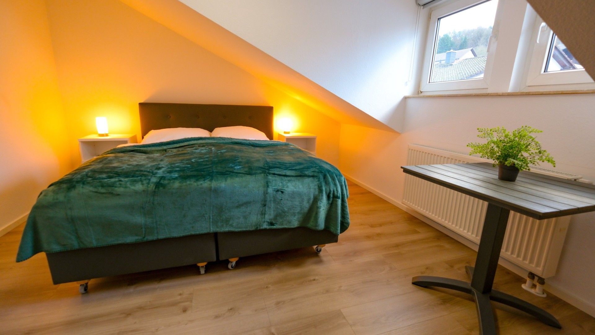 Une chambre à coucher avec un lit, deux lampes de chevet, un radiateur et une fenêtre.
