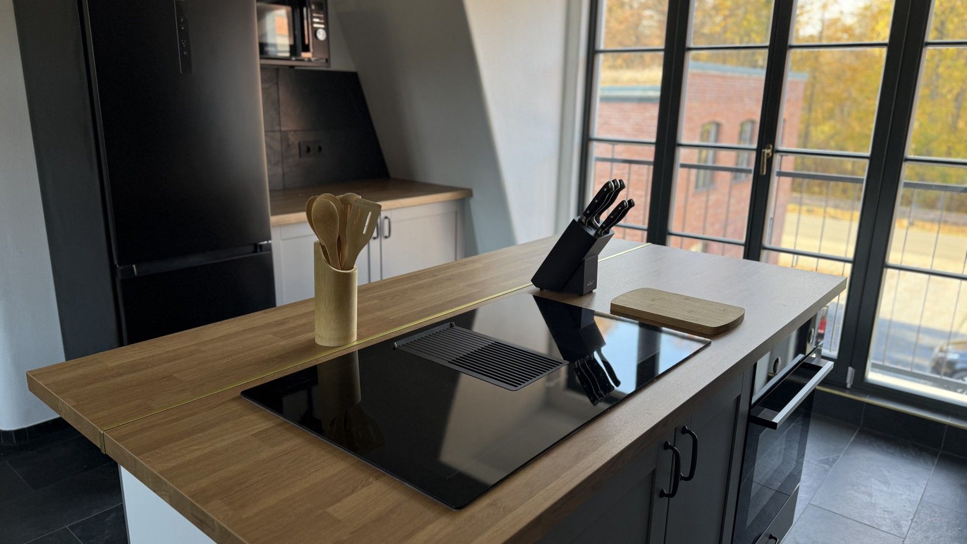 A modern kitchen with a wooden countertop, a built-in stove, and a knife block.