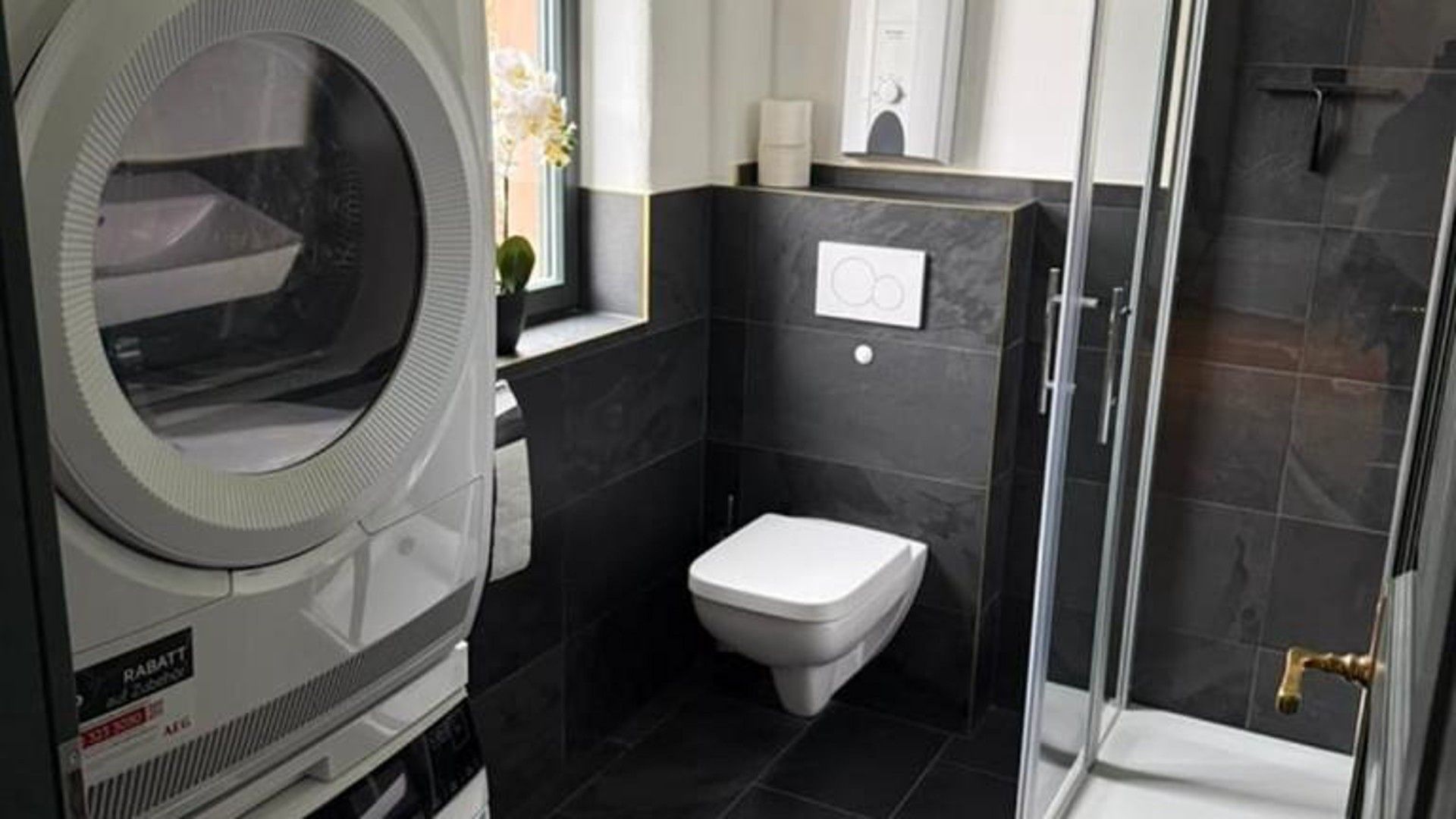 Ein kleines Badezimmer mit Toilette, Dusche und integrierter Waschmaschine.
