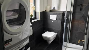 Ein kleines Badezimmer mit Toilette, Dusche und integrierter Waschmaschine.