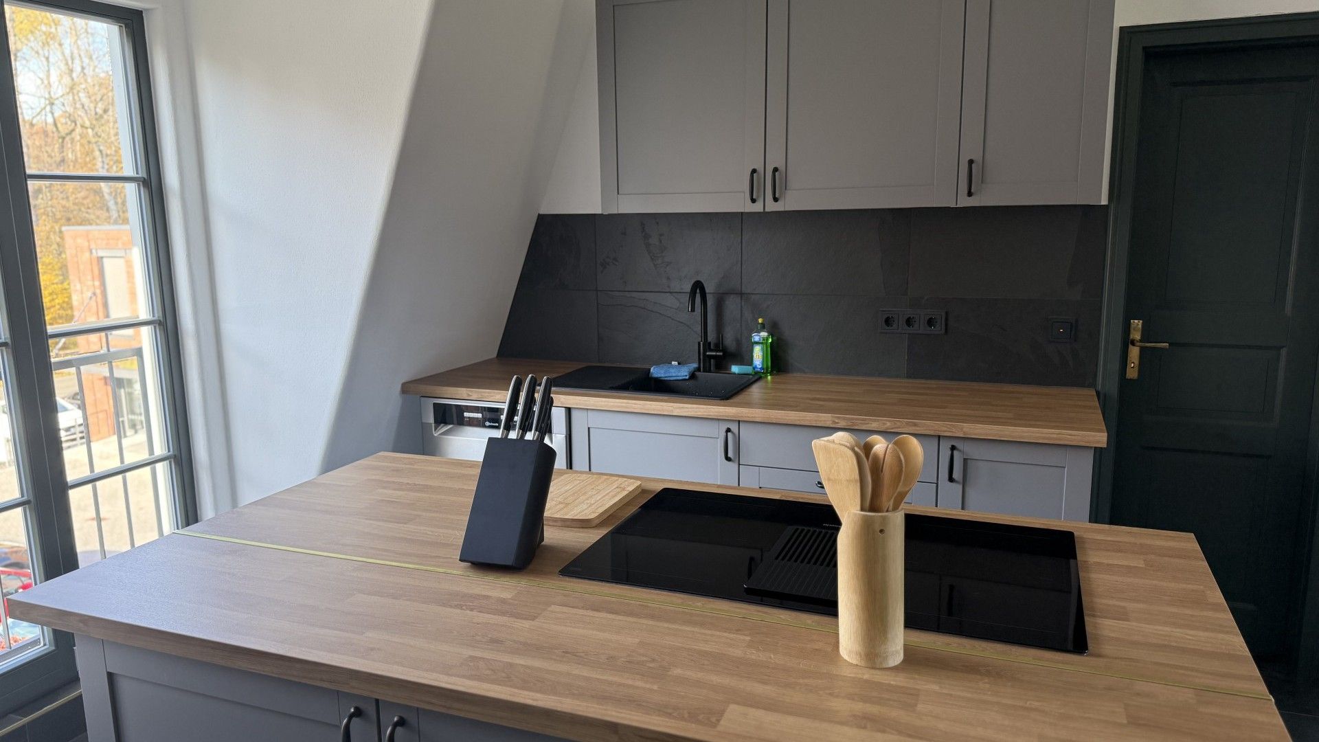 A modern kitchen with a wooden countertop, a black sink, and a built-in stove.