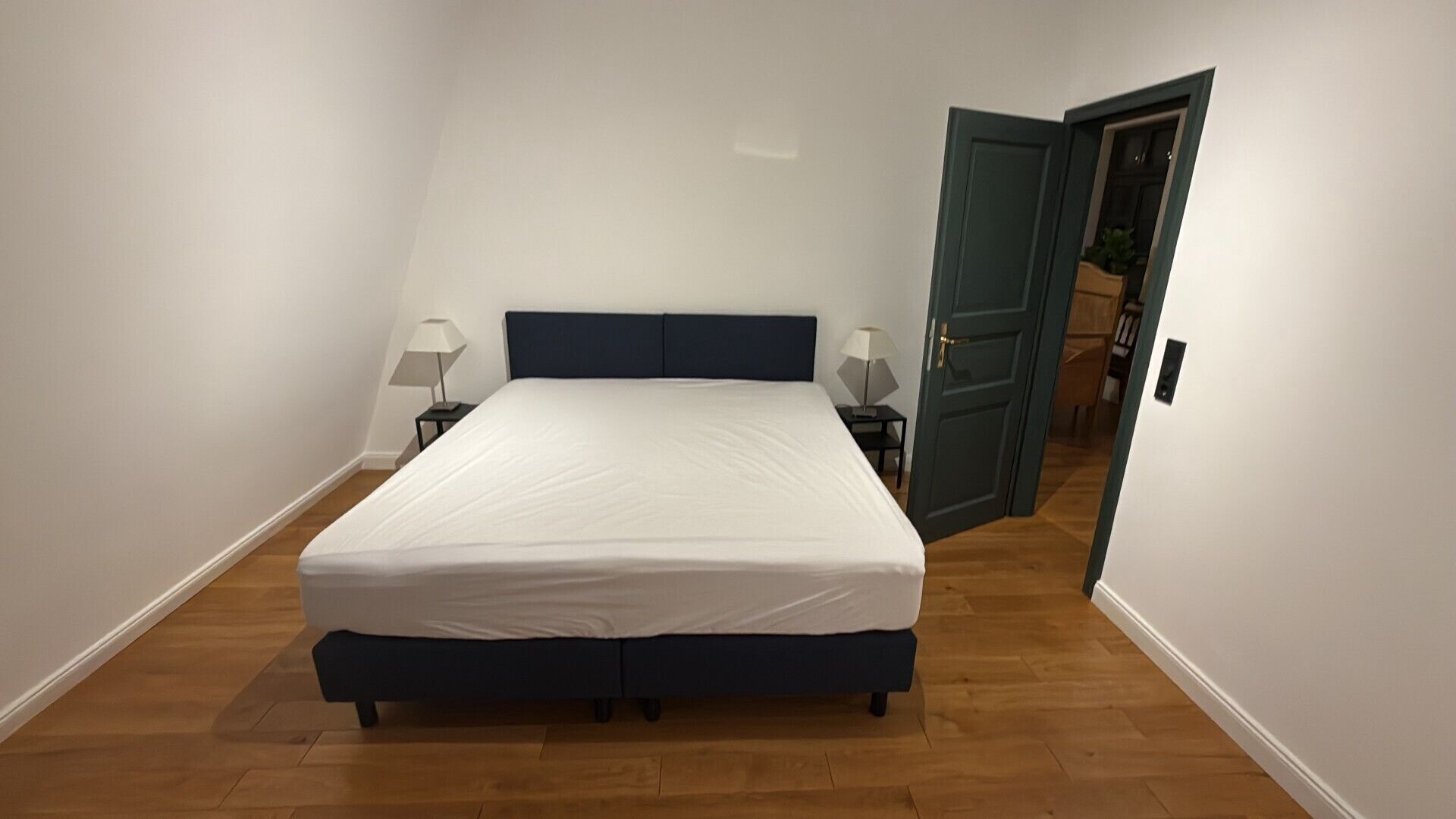 Ein Schlafzimmer mit einem Einzelbett, zwei Nachttischen und einer Tür zu einem anderen Raum.