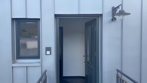 La porta d'entrada d'un edifici, una finestra i un lluminari fixat a la paret.