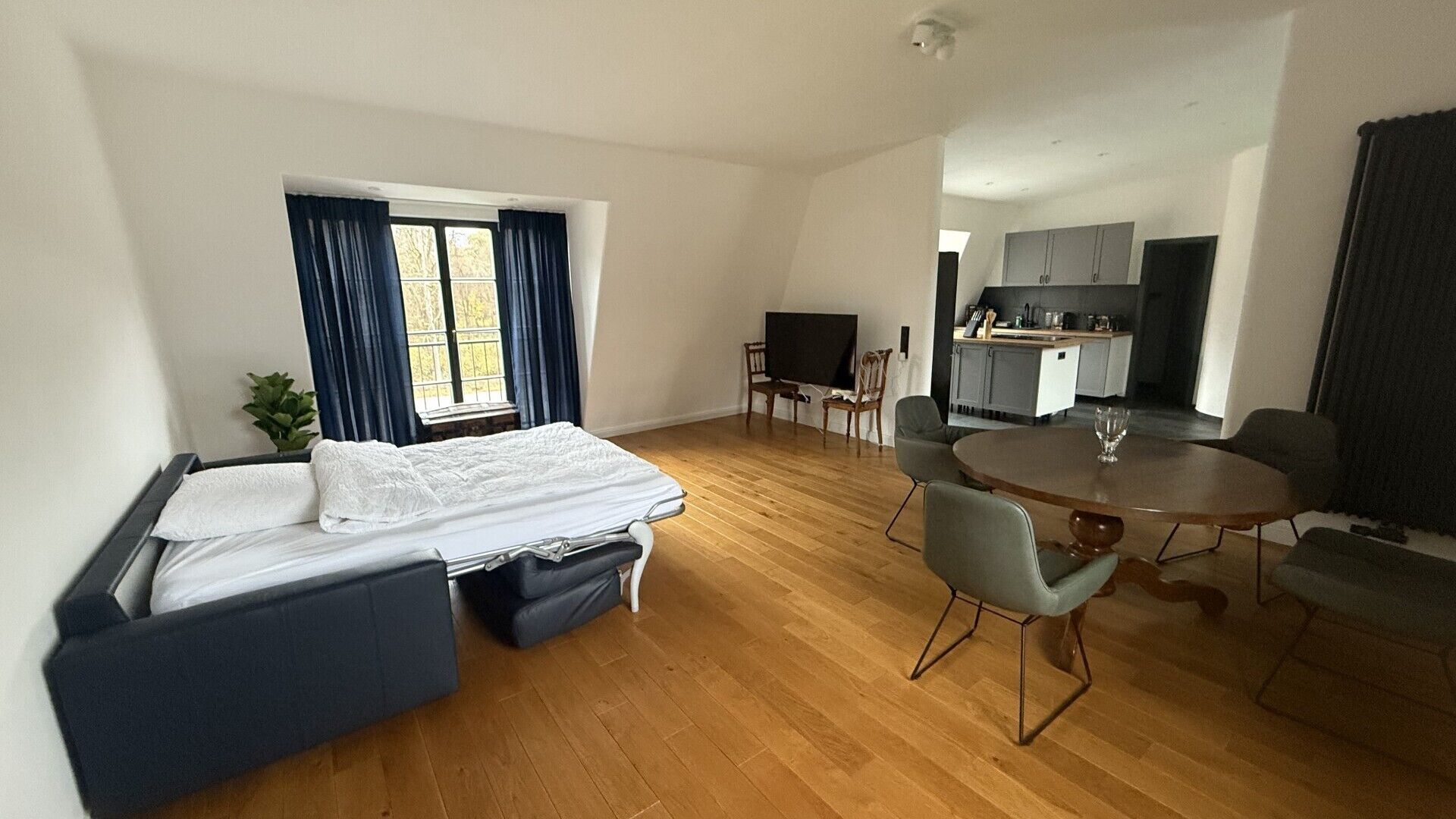 Et moderne hotelværelse med seng, spisebord, fjernsyn og tekøkken.