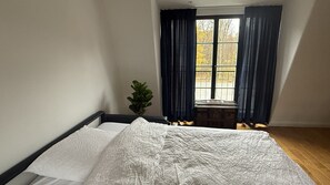 Un dormitorio con cama, ventana con cortinas y una planta.