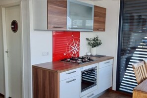 Una cocina moderna con horno empotrado, cocina a gas y un panel decorativo rojo.
