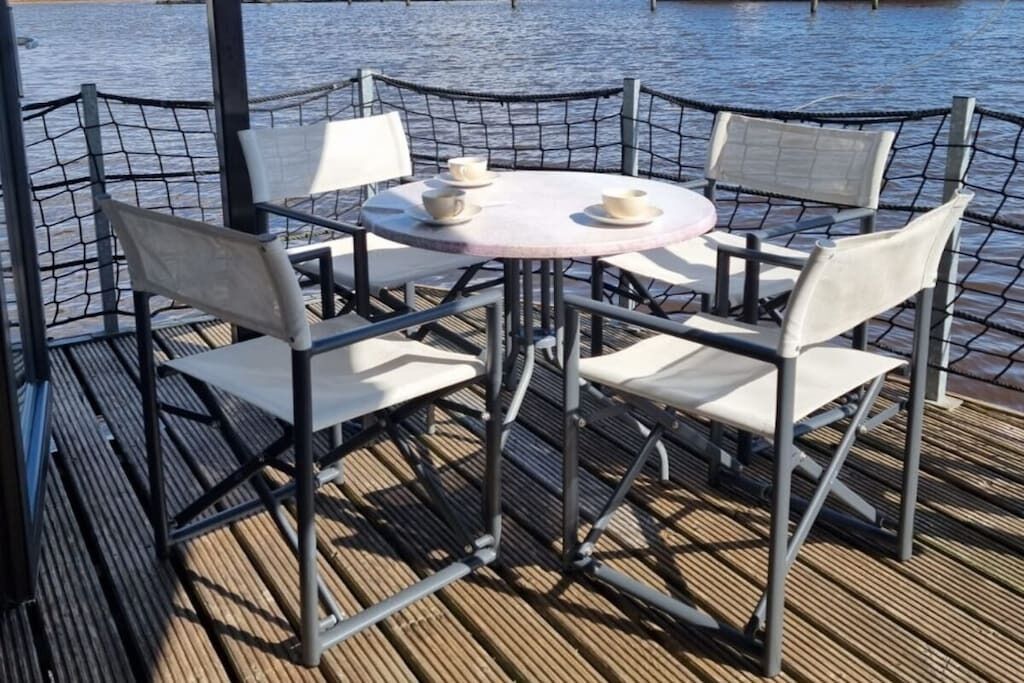 Une table avec quatre chaises et deux tasses dessus, entourée d’une clôture en métal.