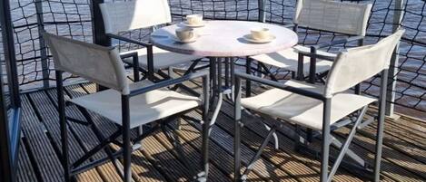A table with four chairs and two cups on it, surrounded by a metal fence.