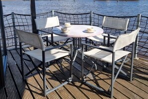 A table with four chairs and two cups on it, surrounded by a metal fence. - Houseboat in Anjum with swimming pool (Anjum)