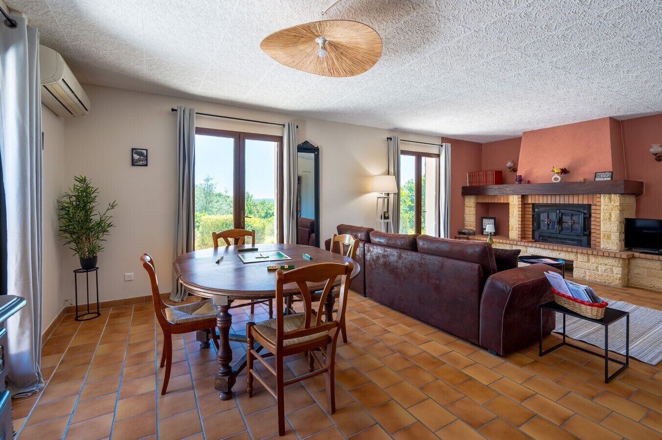 A living room with a fireplace, a dining area with a table and chairs, and a sofa.