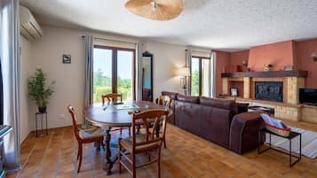 A living room with a fireplace, a dining area with a table and chairs, and a sofa.