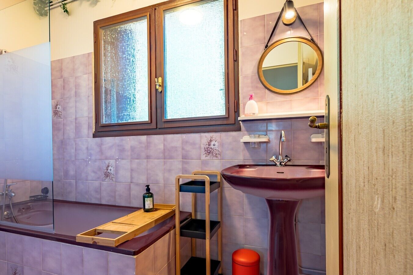 Een badkamer met een bad, een wastafel, een spiegel en een raam.