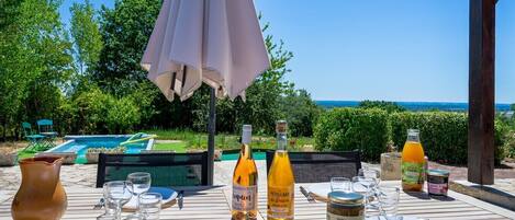An outdoor dining area with a table set for two, a bottle of wine, and various condiments.