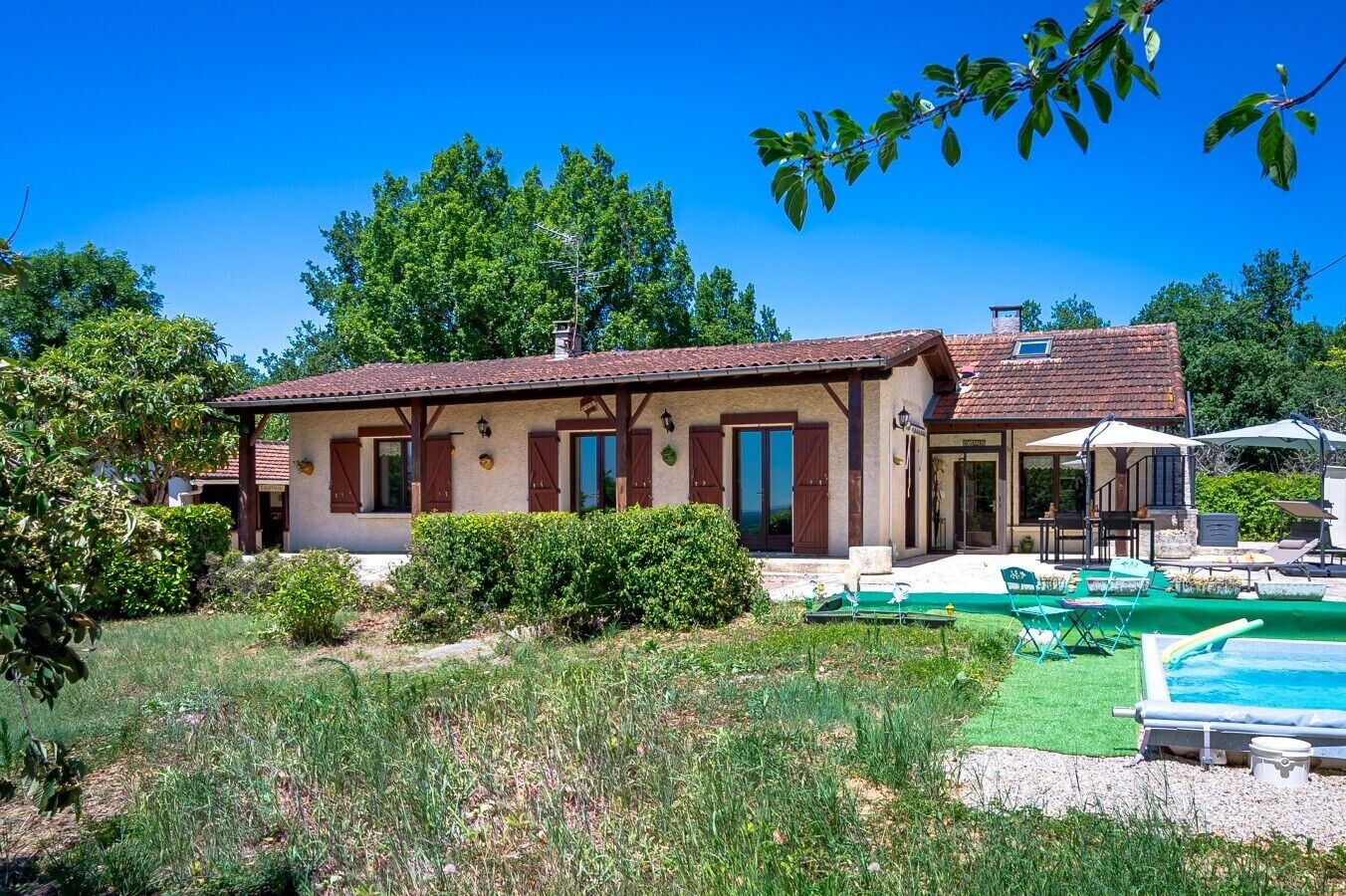 A two-story house with a swimming pool, a covered patio, and a garden.