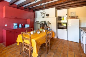 Una cocina compacta con armarios rojos, una mesa de comedor con mantel amarillo y una lavadora.