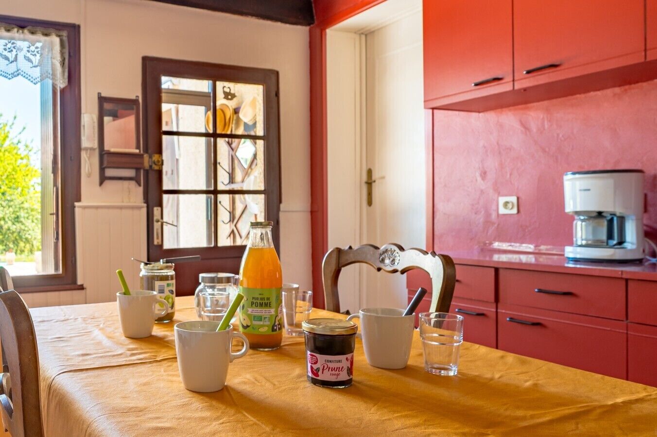 A dining table with various items including a bottle of juice, a mug, and a jar of jam.