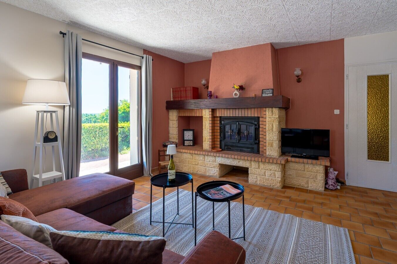 A living room with a fireplace, a sofa, a TV, and a floor lamp.