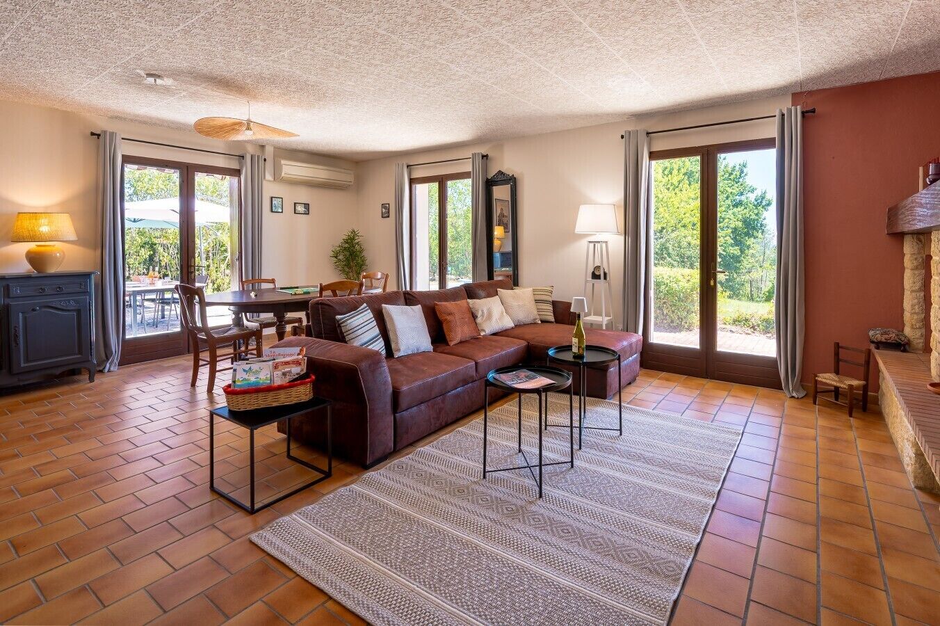 A living room with a brown leather sofa, a coffee table, and a dining area with a table and chairs.