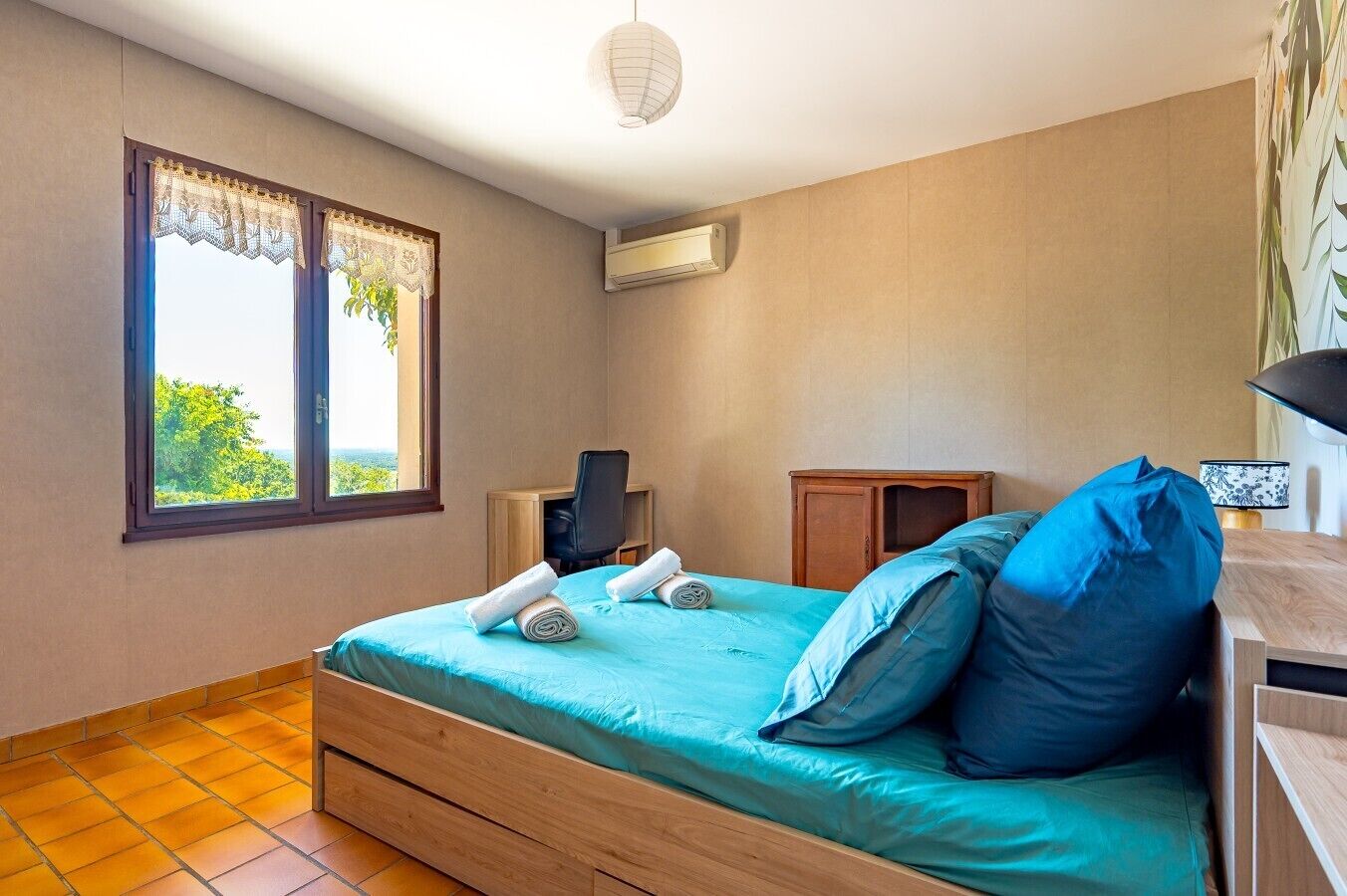 Ein Schlafzimmer mit Bett, Schreibtisch, Klimaanlage und einem Fenster mit Blick.