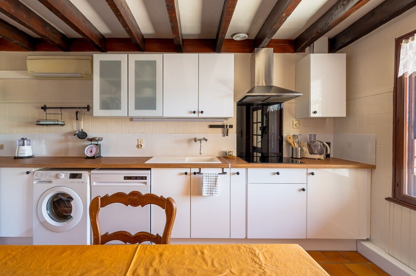 Une cuisine compacte avec des meubles blancs, un four encastré et un lave-linge.