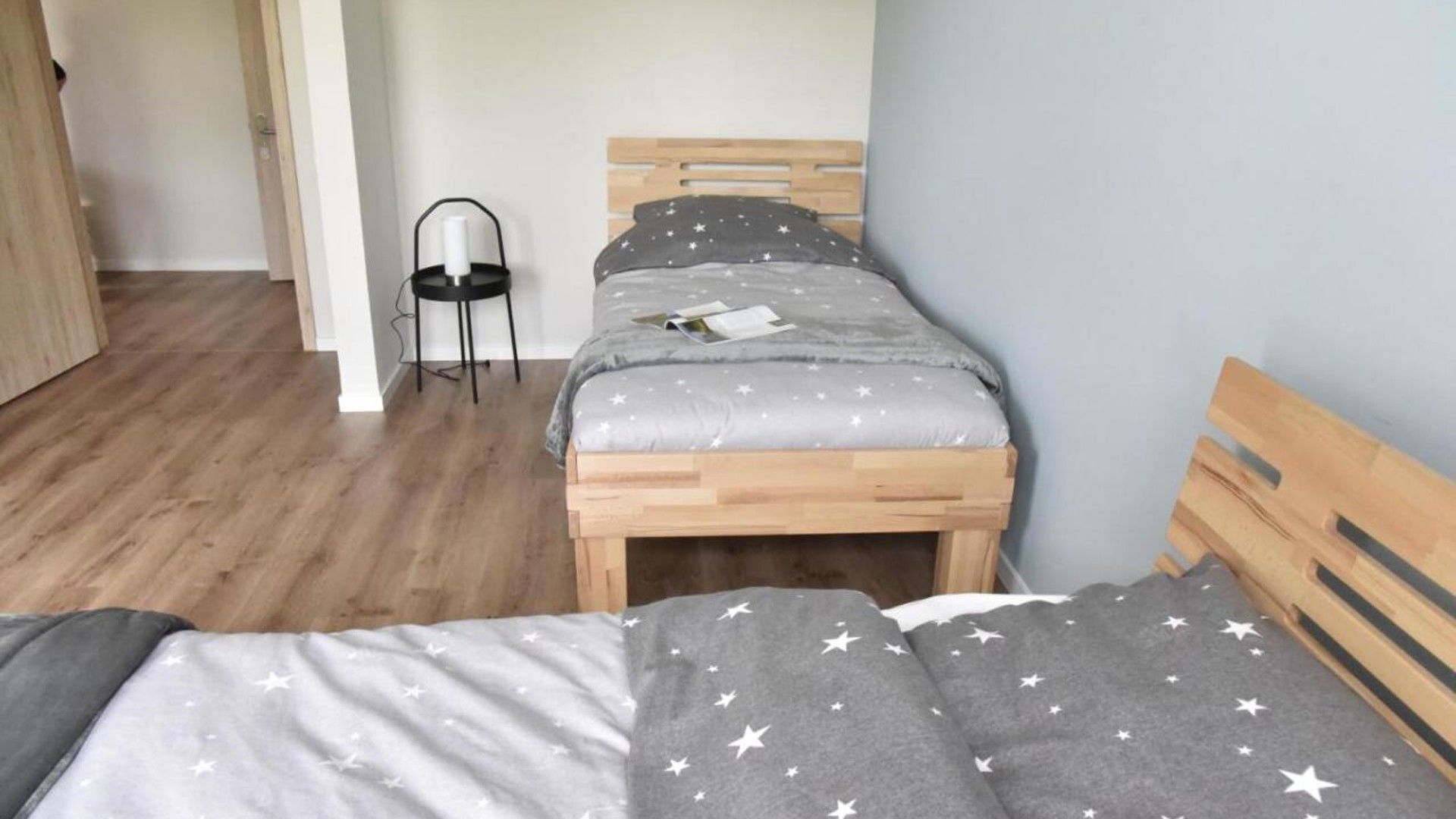 Ein Schlafzimmer mit einem Bettgestell aus Holz, einem Nachttisch und einem Sessel.
