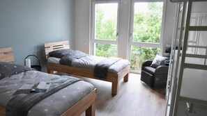 Ein Schlafzimmer mit zwei Betten, einem Fenster und Blick ins Grüne.