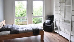 Quarto com cama, uma cadeira e um guarda-roupa branco.