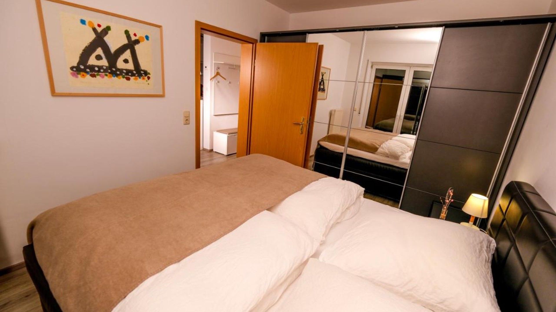 Une chambre à coucher comprenant un lit, une armoire, un miroir et une porte donnant sur une salle de bain.