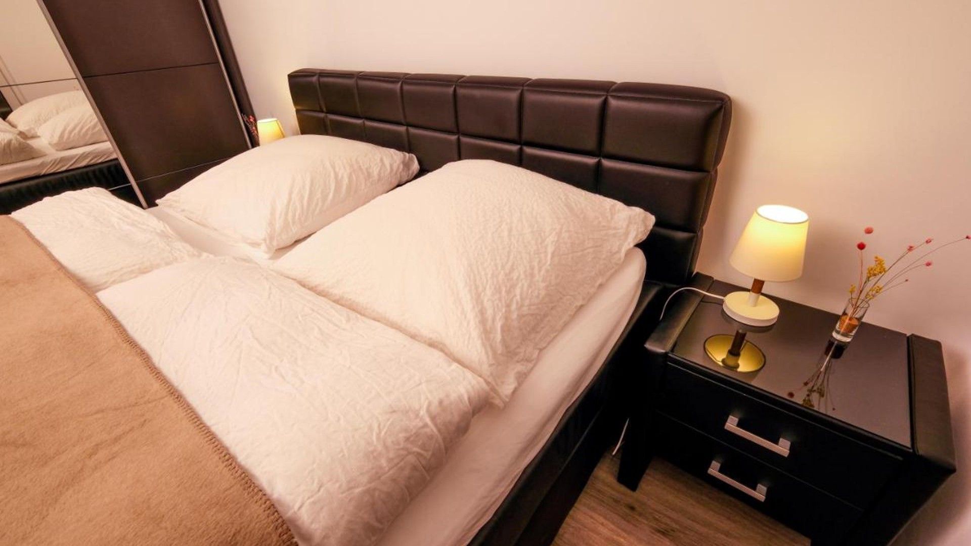 Ein Hotelzimmer mit Bett, Nachttisch und Lampe sowie einem Spiegel.