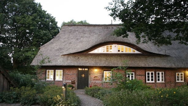 A traditional thatched-roof house with a brick facade, a central door, and a pathway leading to the entrance. - Holiday home in Hanstedt with swimming pool (Hanstedt)