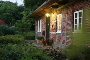 A brick house with a stone pathway leading to the entrance, surrounded by greenery. - Holiday home in Hanstedt with swimming pool (Hanstedt)