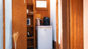 Una cocina compacta con refrigerador, cafetera y microondas.