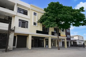 A multi-story building with a central entrance, a staircase on the left, and a tree in front.
