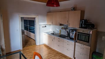A compact kitchen with wooden cabinets, a built-in oven, and a coffee machine.