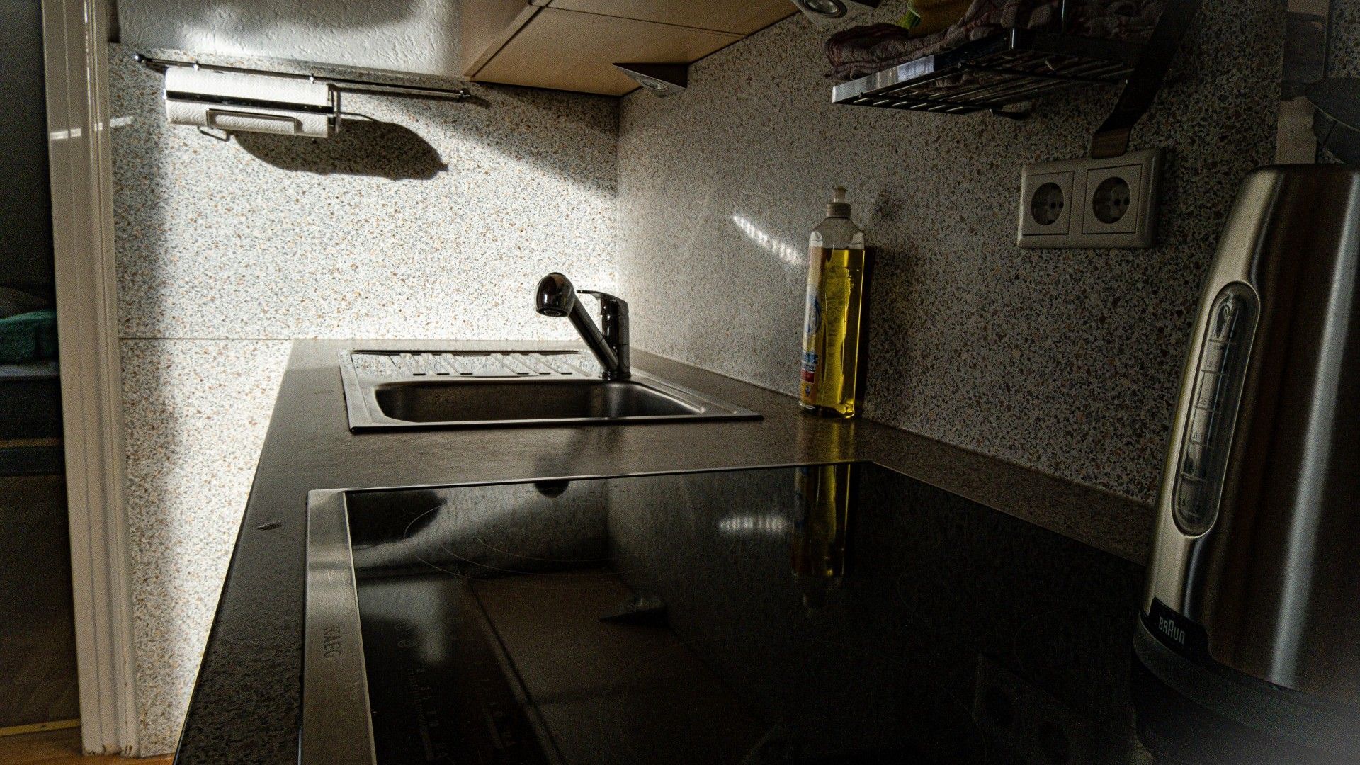 Een keuken met een RVS spoelbak, een fles kookolie en een Braun koffiezetapparaat.