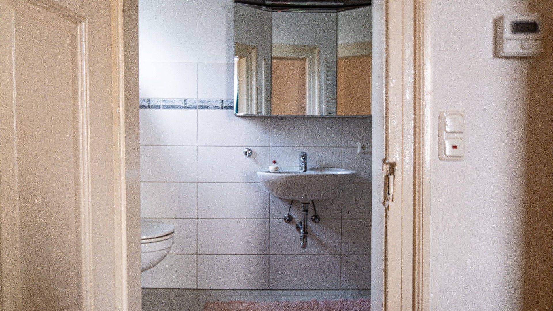 A bathroom with a white sink, a mirror above it, and a toilet.