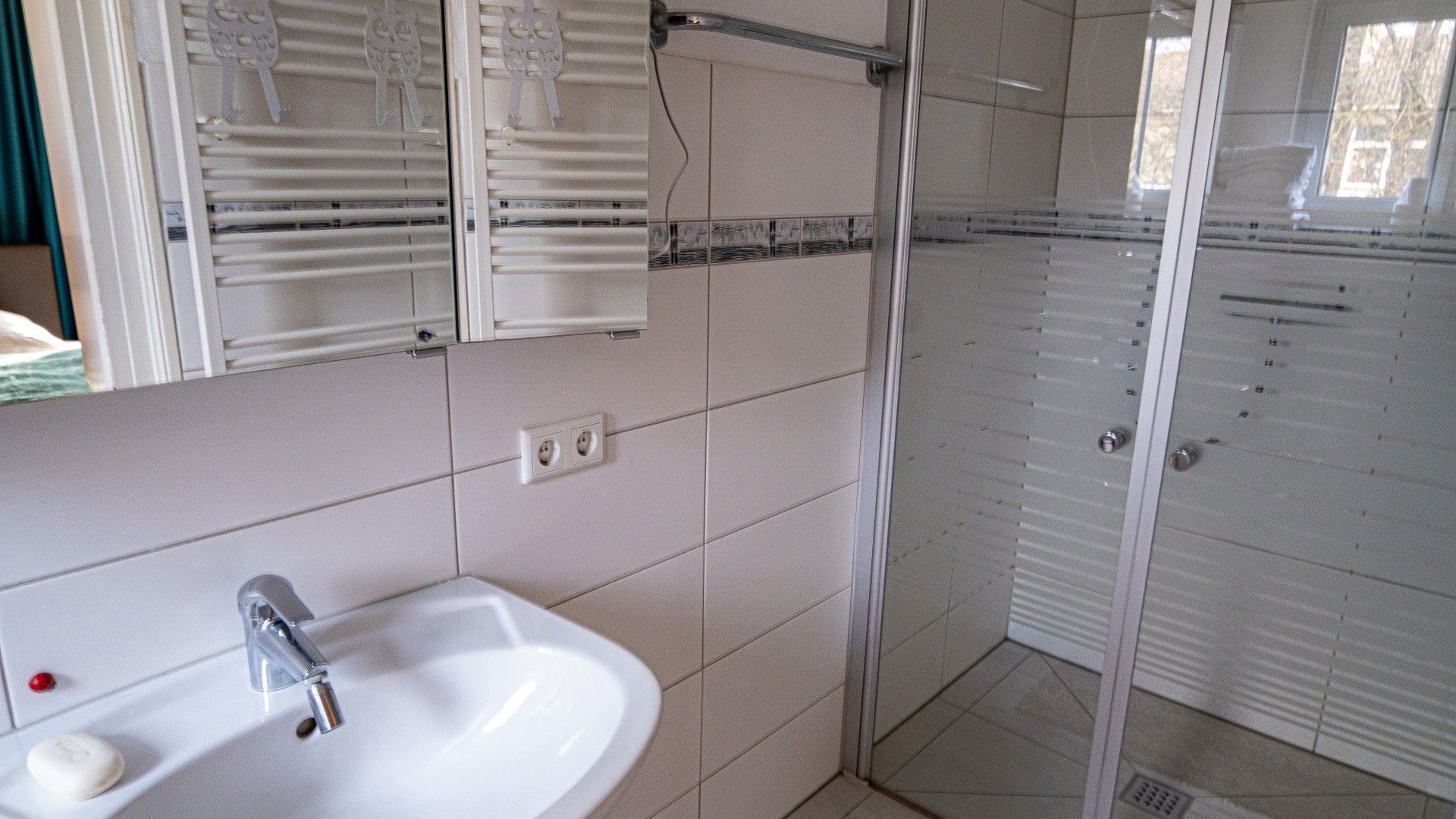 Une salle de bain avec un lavabo blanc, un miroir et une douche.