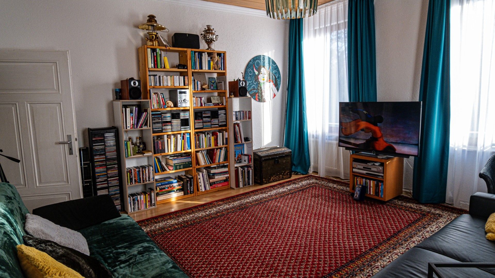 Un salon avec une grande bibliothèque, un téléviseur et un tapis à motifs.
