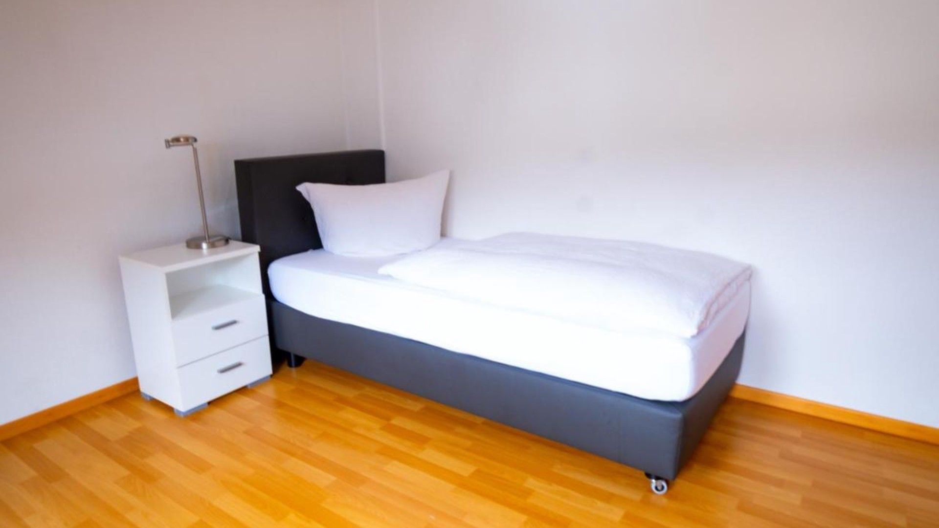 Ein Schlafzimmer mit einem Bett, einem Nachttisch und einer Lampe.