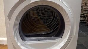 A front view of a washing machine with a circular door and a visible drum inside. - Alte Kammfabrik – Garden-Level Studio (Michelstadt)