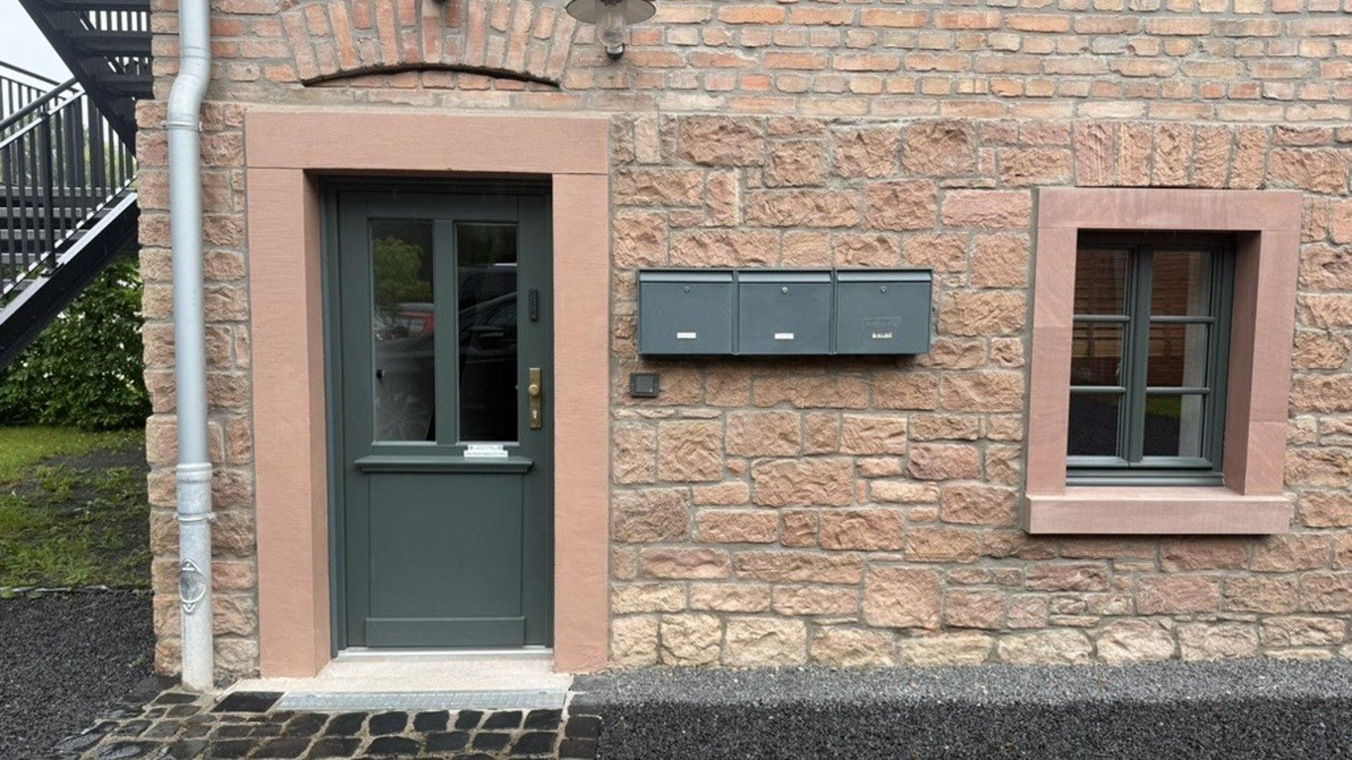Ein Steinhaus mit einer dunkelgrünen Tür und einem Briefkasten.