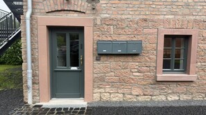 A stone building with a dark green door and a mailbox. - Alte Kammfabrik – Garden-Level Studio (Michelstadt)