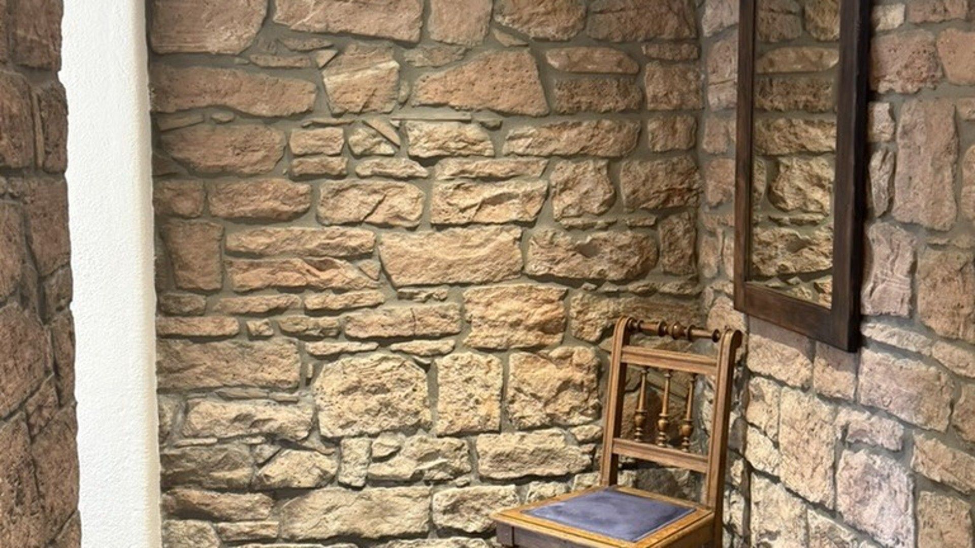 Eine Steinsäule mit einem Holzstuhl und einem kleinen Tisch.