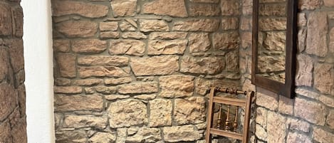 Un muro de piedra con una silla de madera y una pequeña mesa.