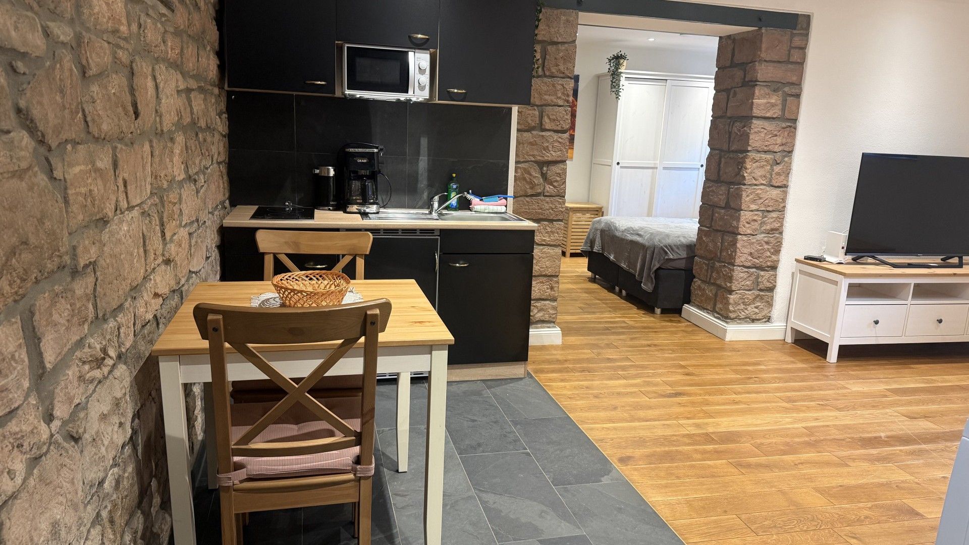 Een ruimtelijk ingerichte leefruimte met een kitchenette, een eethoek en een slaapkamer.