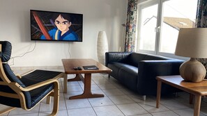 A living room with a television, a sofa, a chair, a coffee table, and a lamp.
