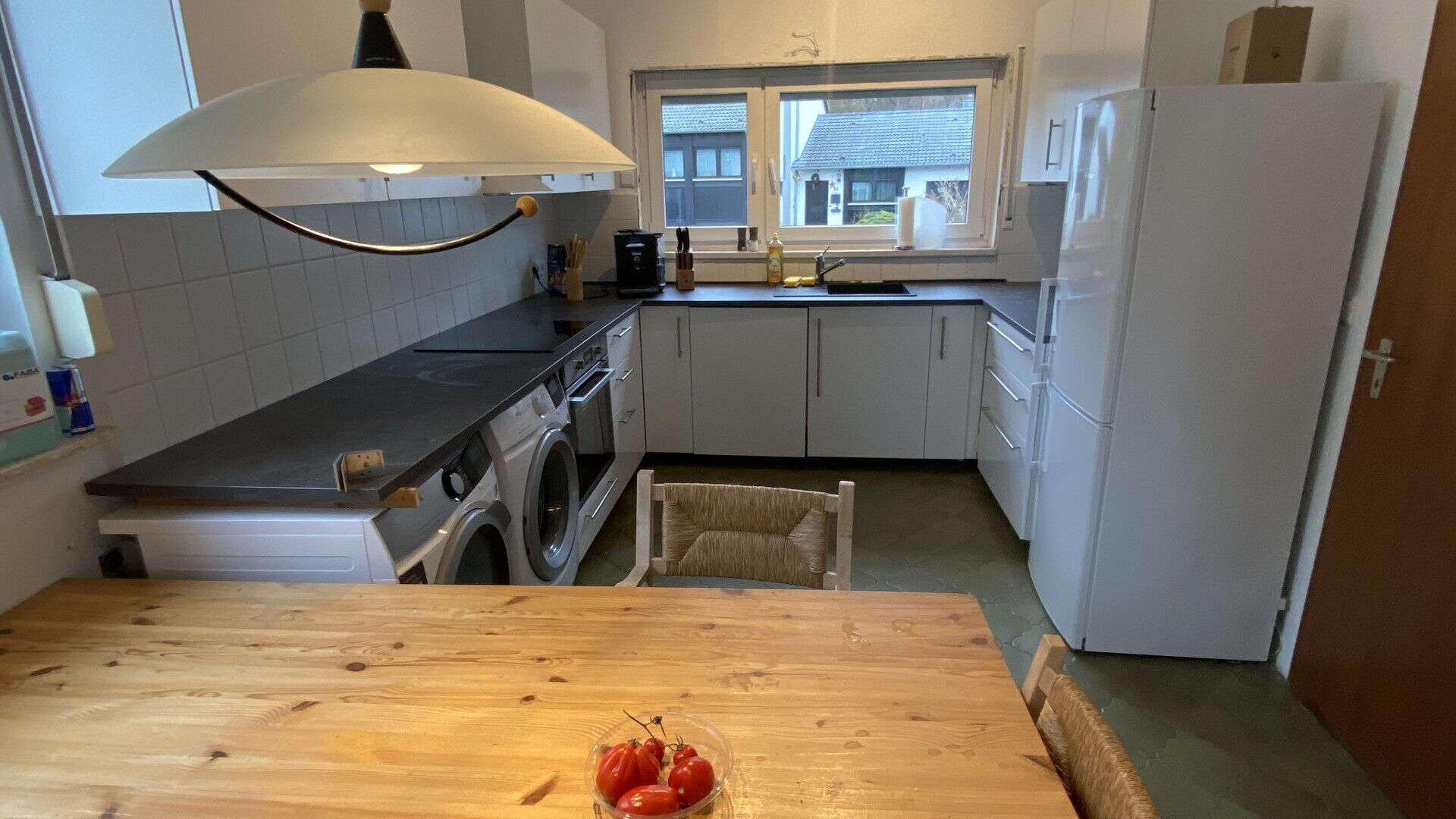 A compact kitchen with a washing machine, a sink, and a window.