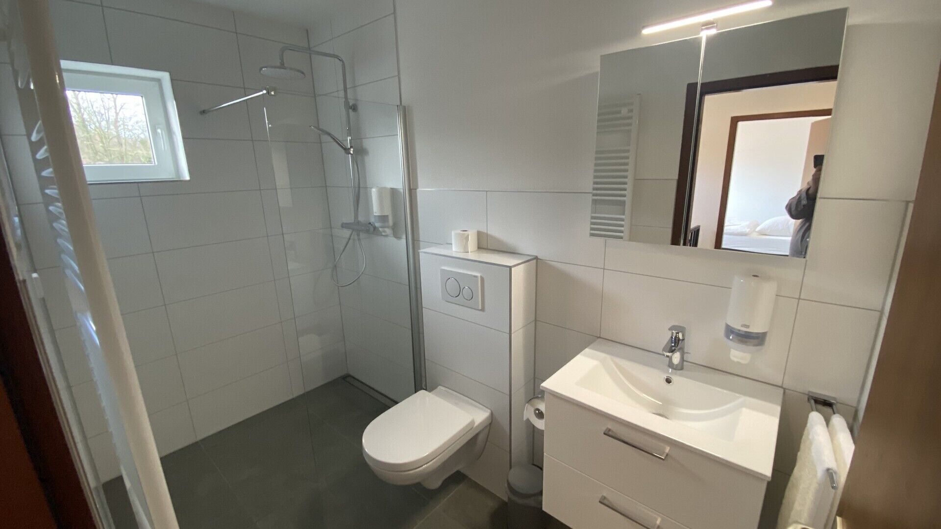 Un baño moderno con ducha, inodoro, lavamanos y espejo.